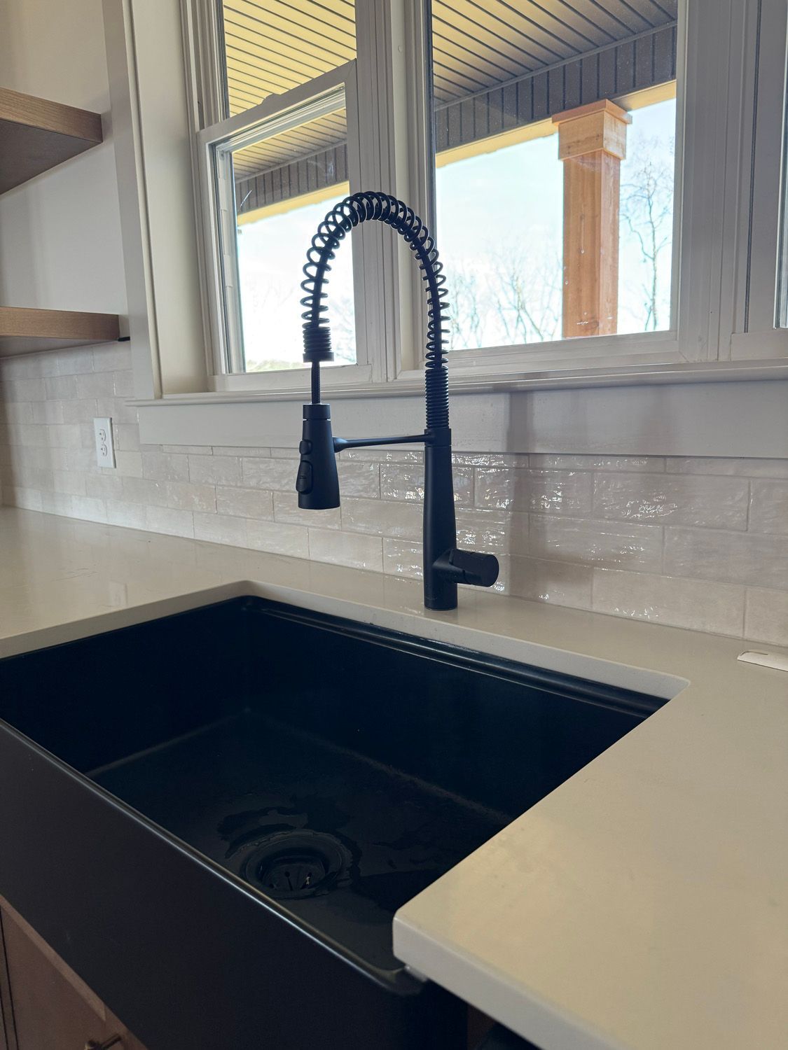 A kitchen sink with a faucet and a window in the background.