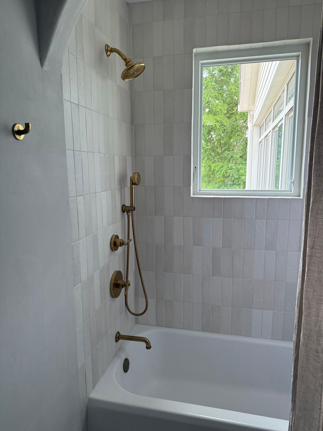 A bathroom with a bathtub , shower , and window.