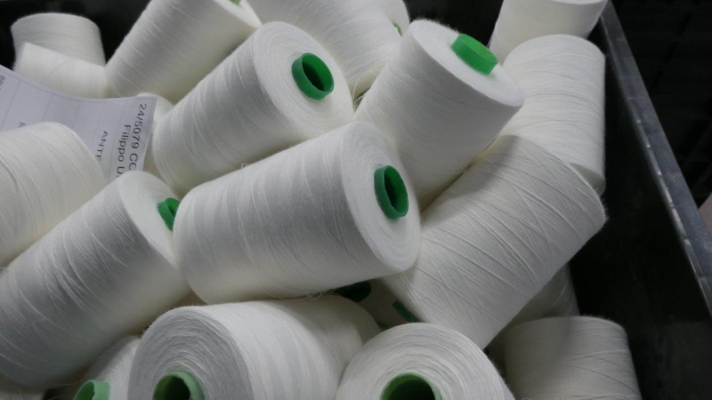 Un contenitore pieno di numerose bobine di filato industriale bianco