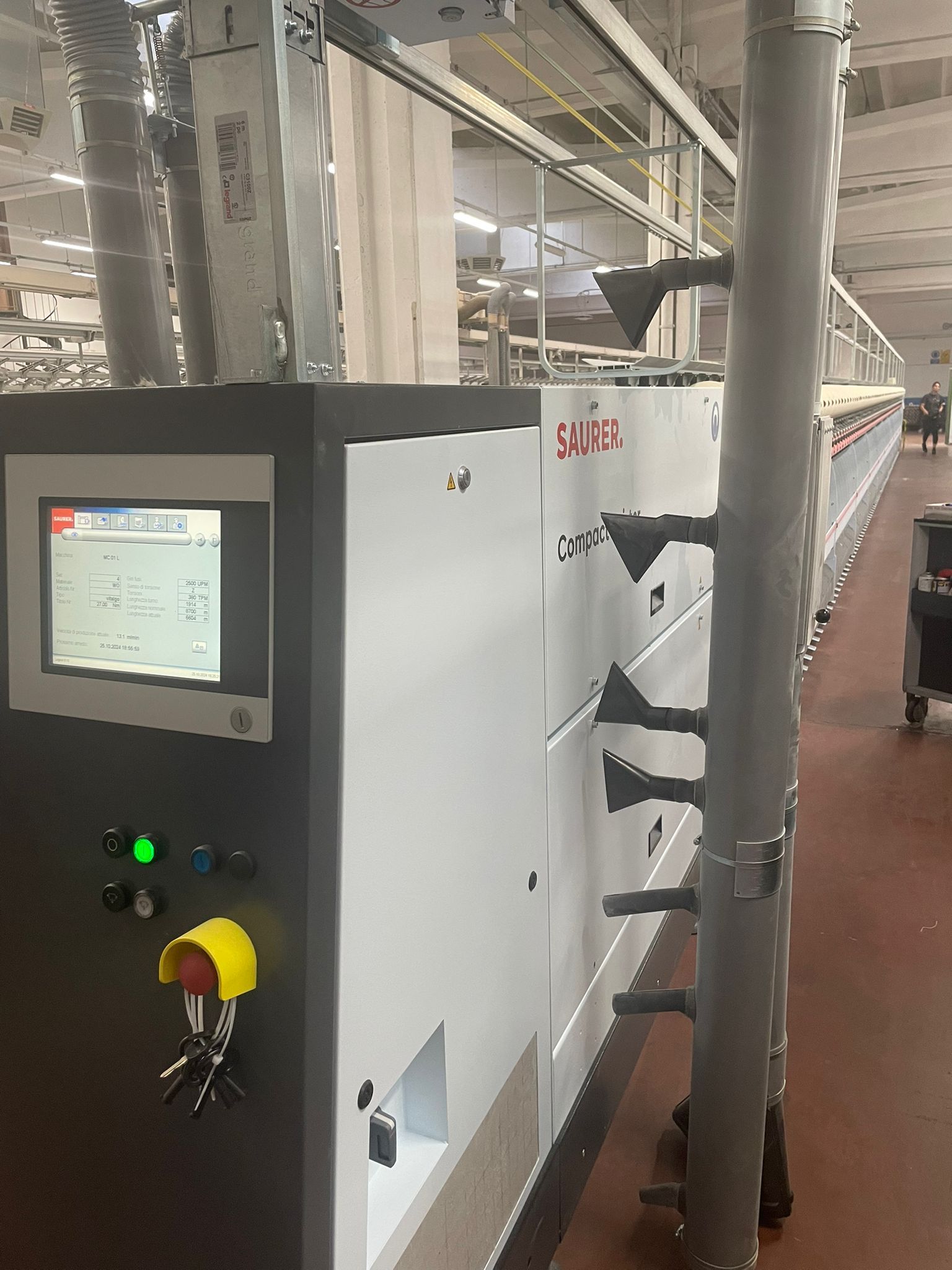 Una macchina tessile Saurer bianca con pannello di controllo digitale e un grande gruppo di tubazioni