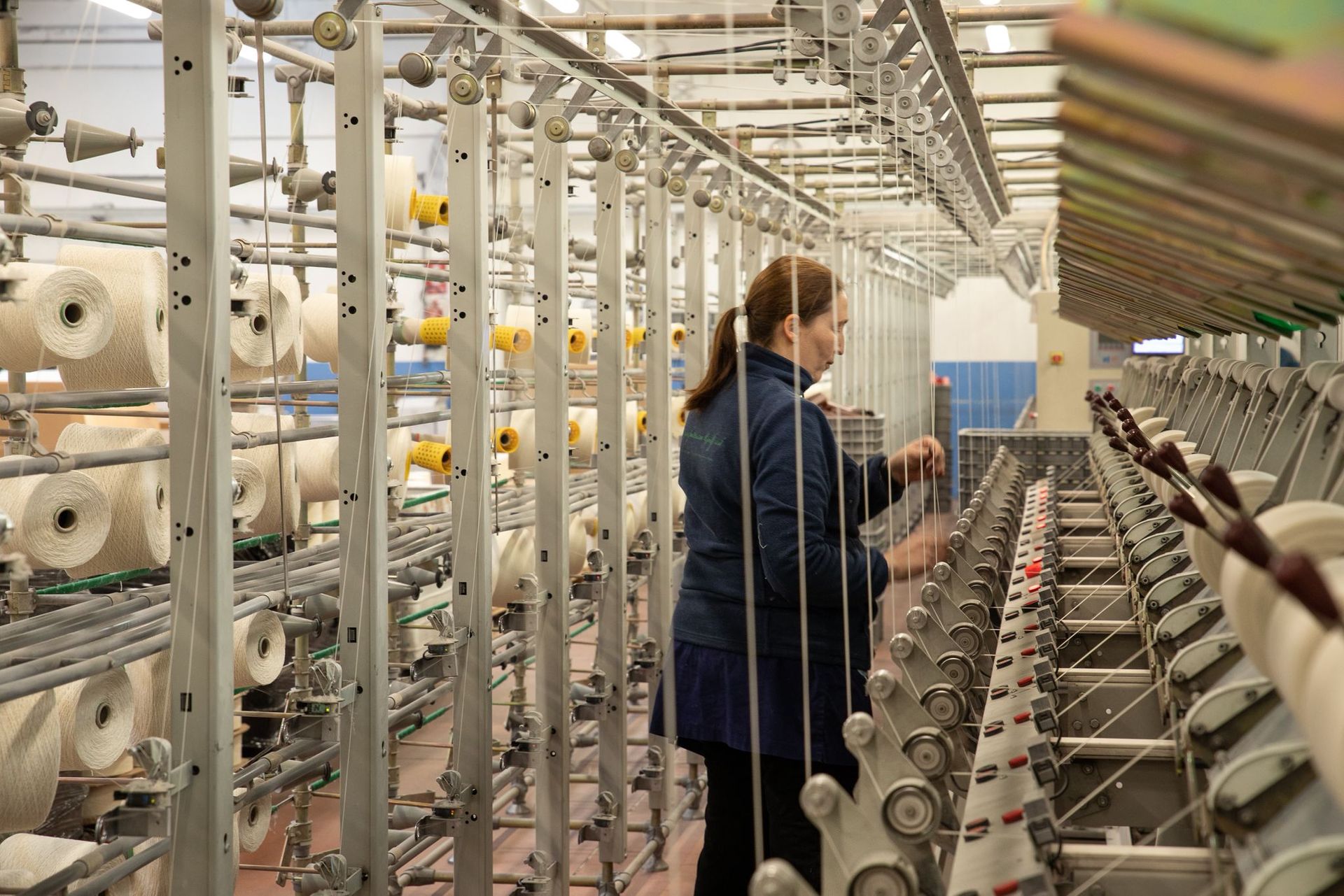 In un ambiente industriale, un operaio controlla i macchinari per la produzione tessile