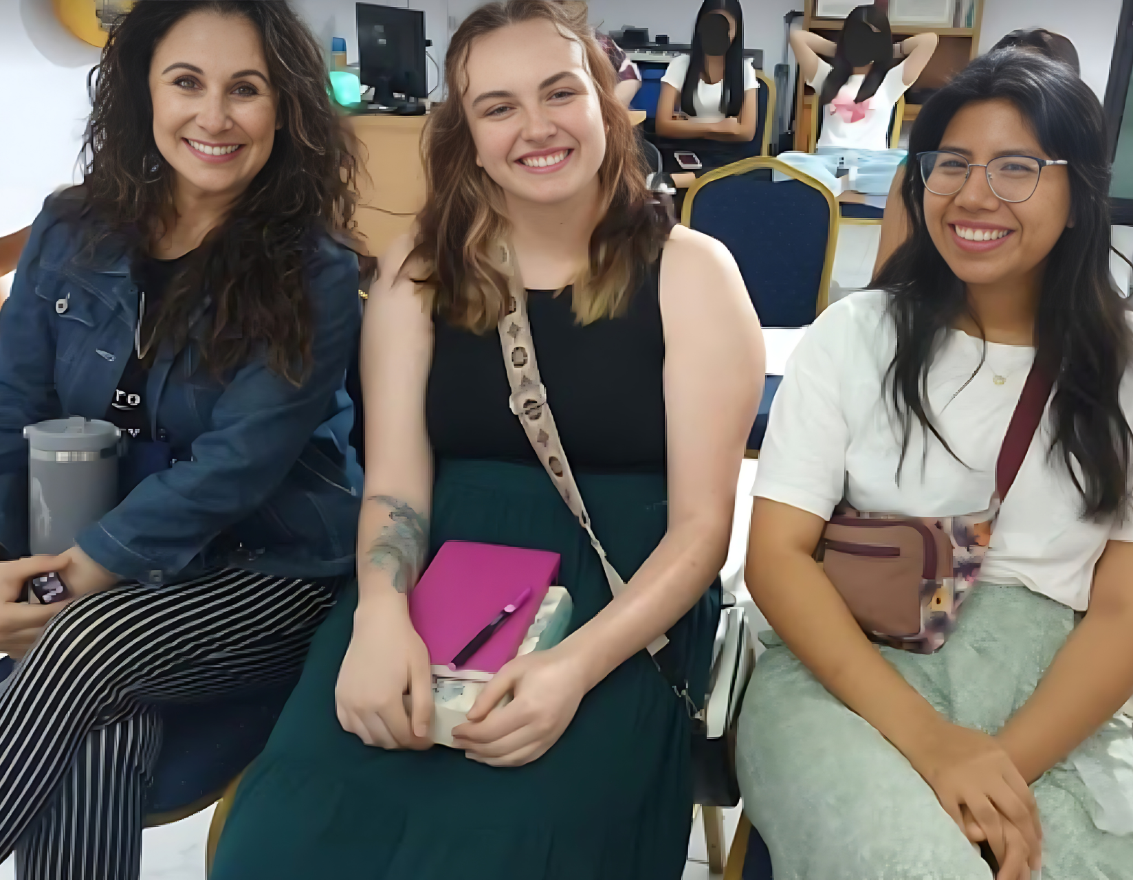 Three women are sitting next to each other and smiling for the camera