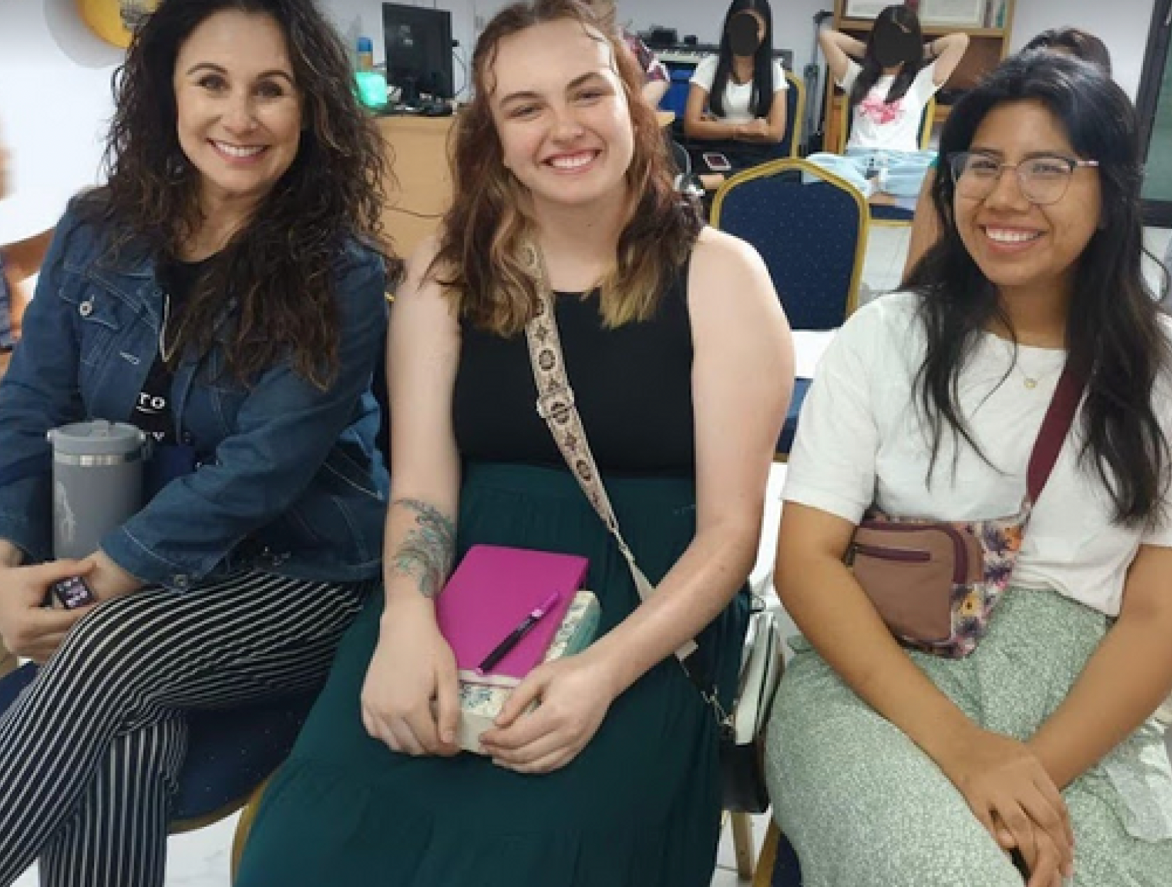 Three women are sitting next to each other and smiling for the camera