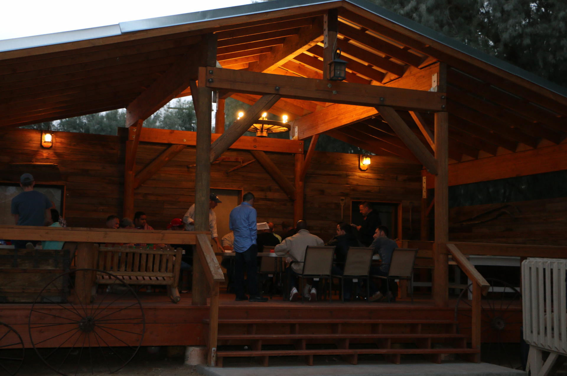 A group of people sitting at tables under a wooden roof