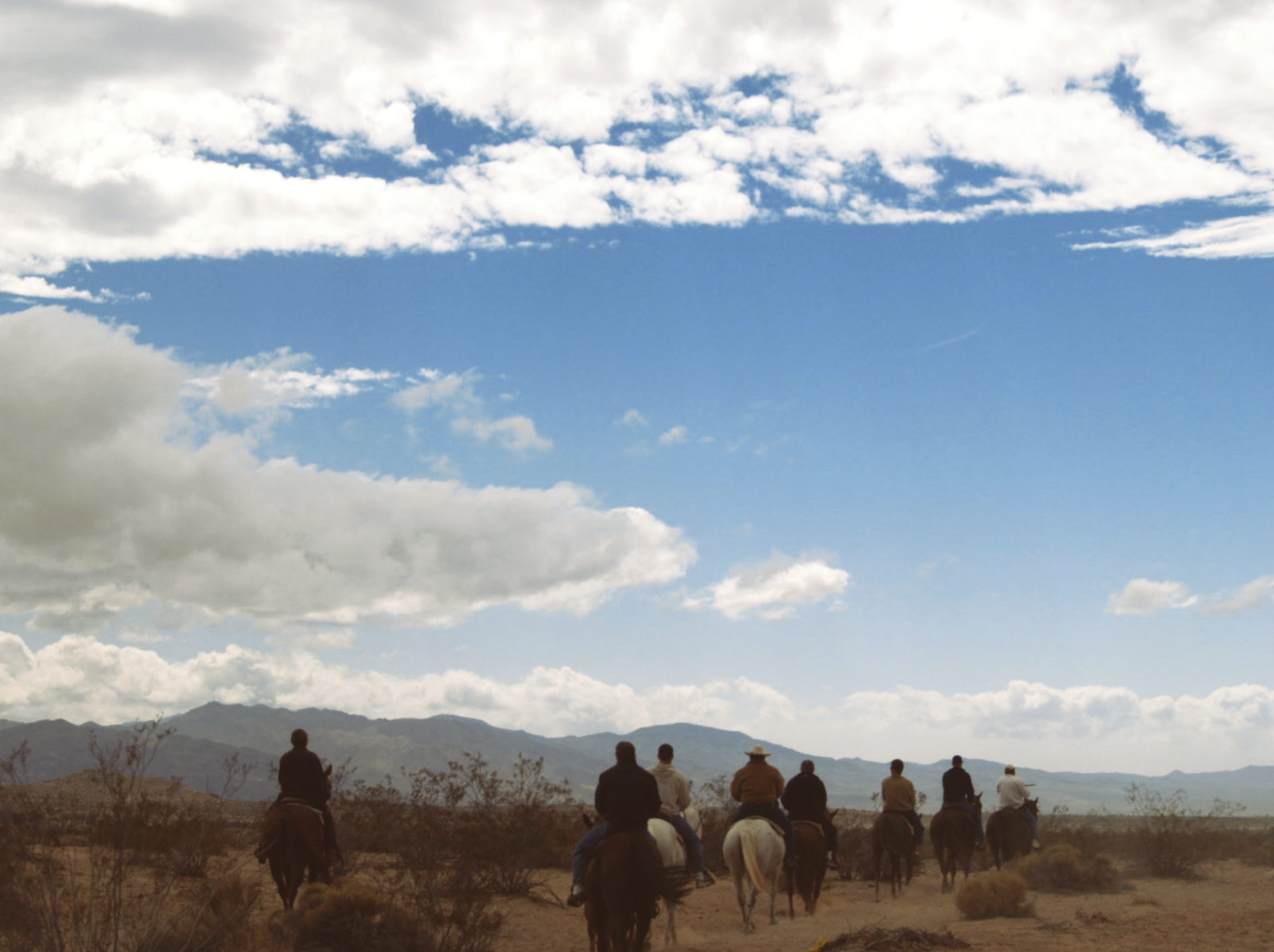 A group of people are riding horses in the desert