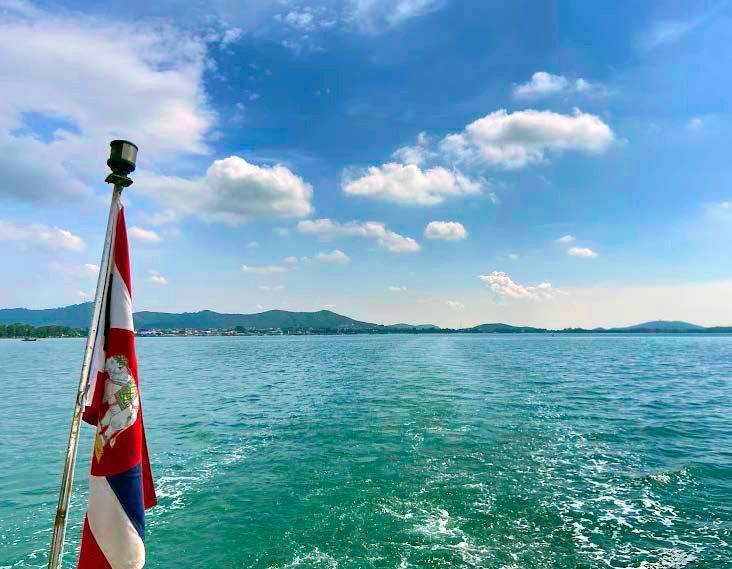 A red white and blue flag is flying over a body of water.