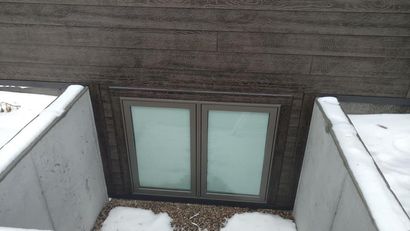 A window in the side of a building with snow on the ground