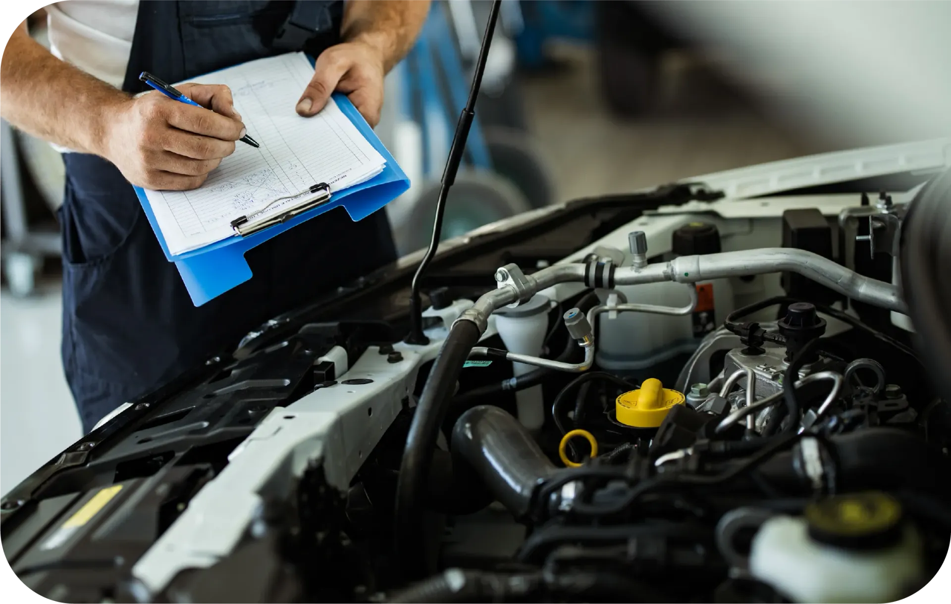 A mechanic is writing on a clipboard while looking under the hood of a car.