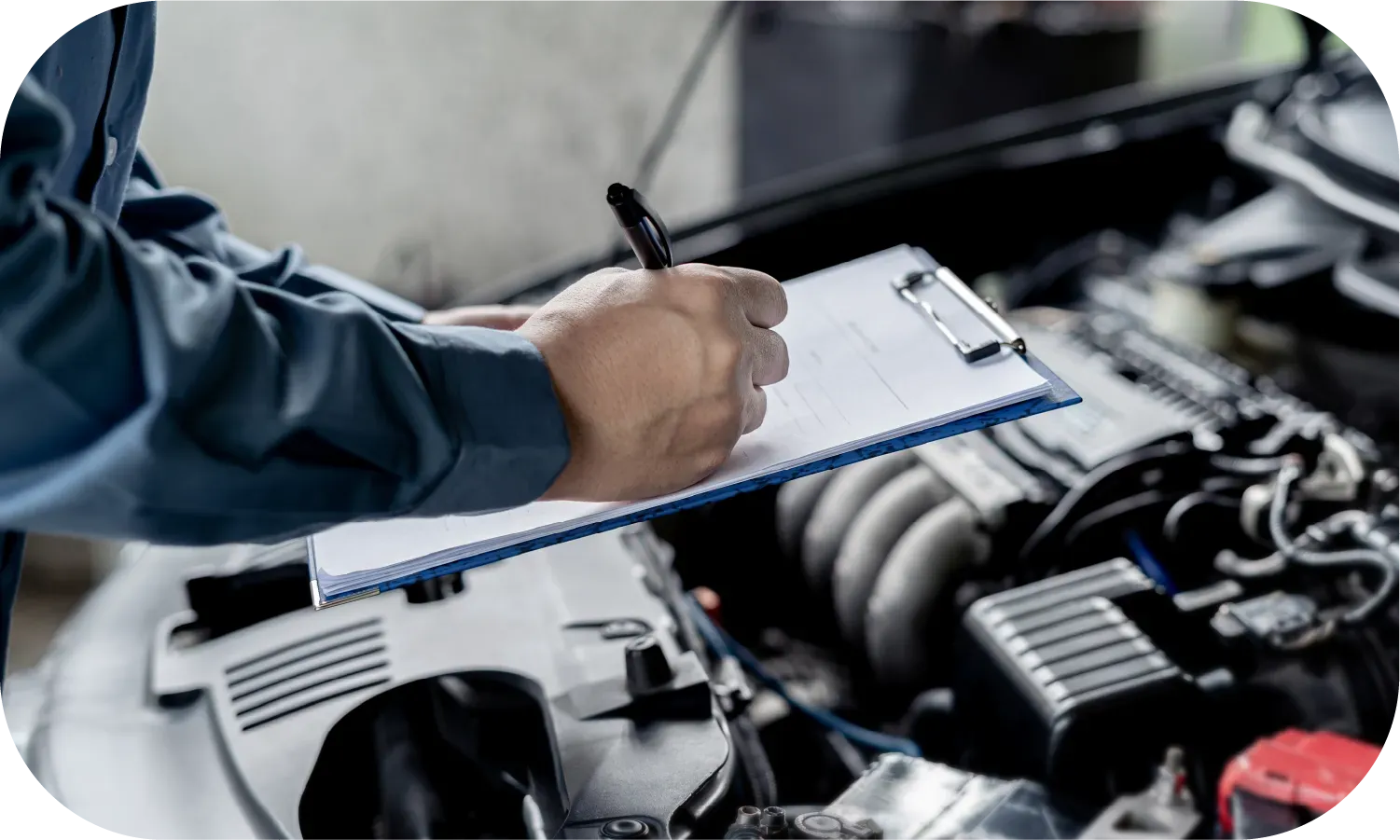 A mechanic is writing on a clipboard while working on a car.