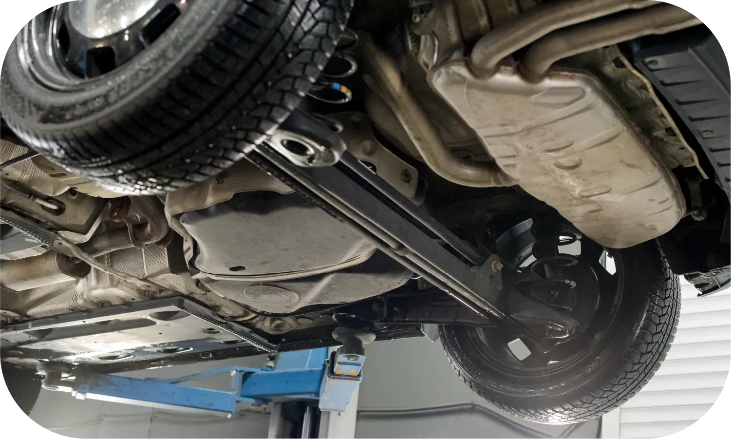 The underside of a car is shown on a lift.