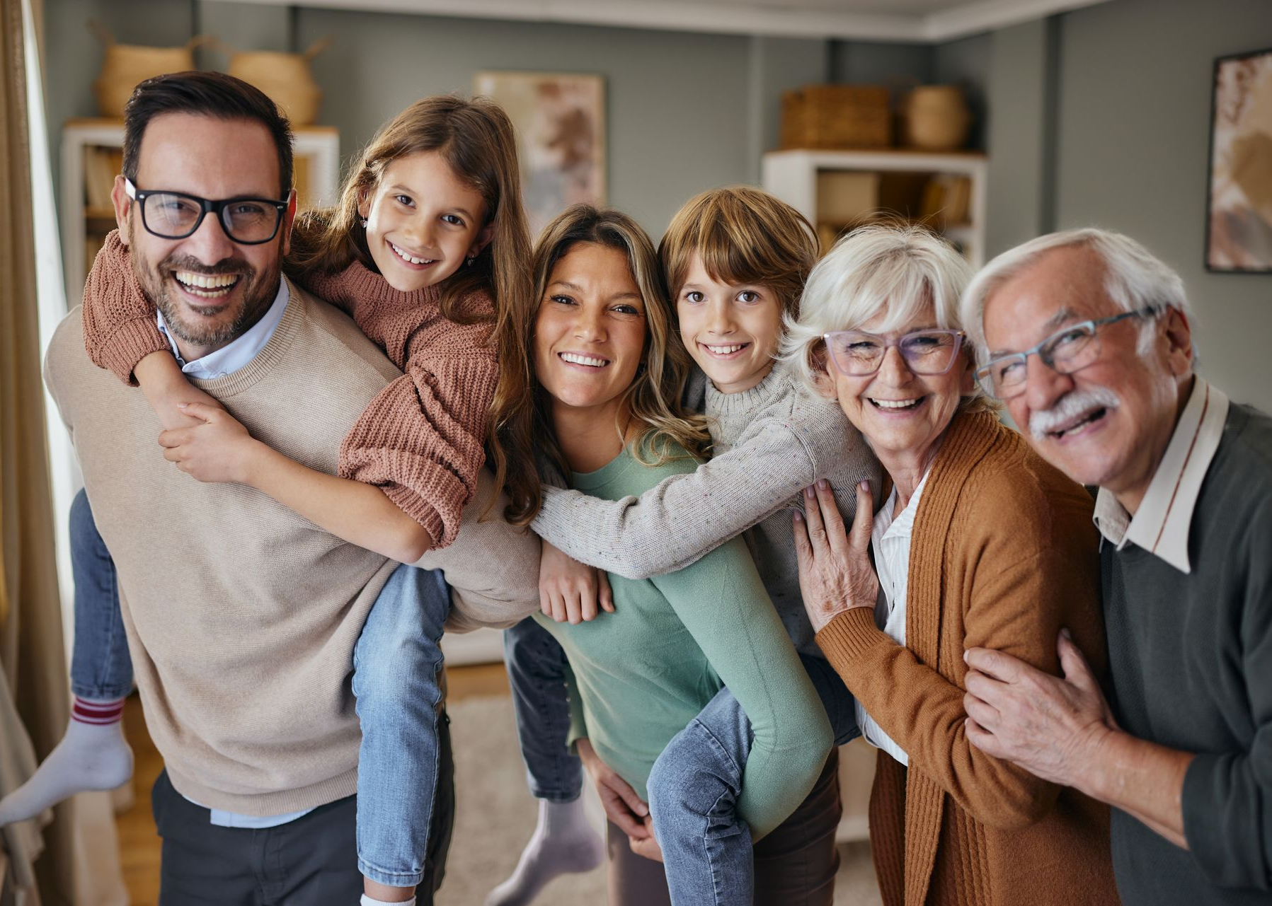 Smiling family group posing indoors, with two adults and three children in cozy sweaters