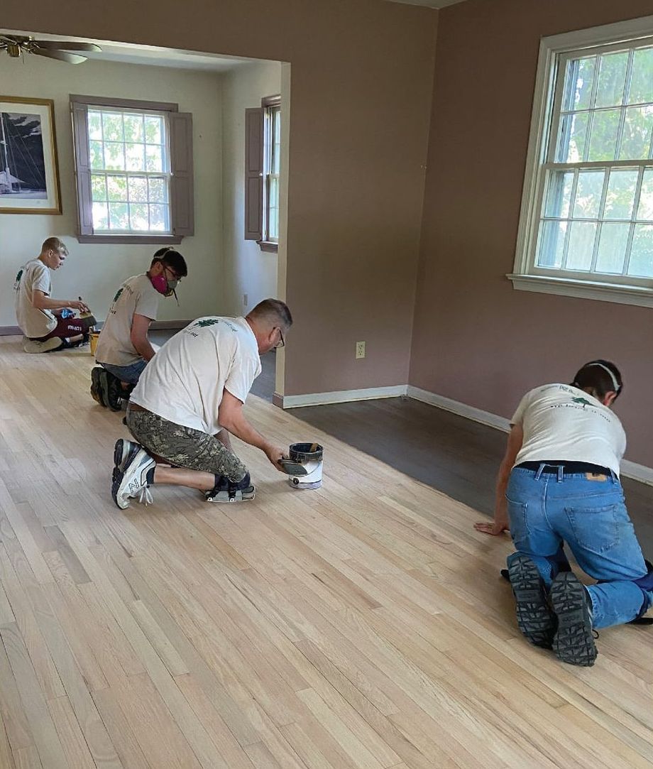 A group of men are working on a wooden floor in a room.