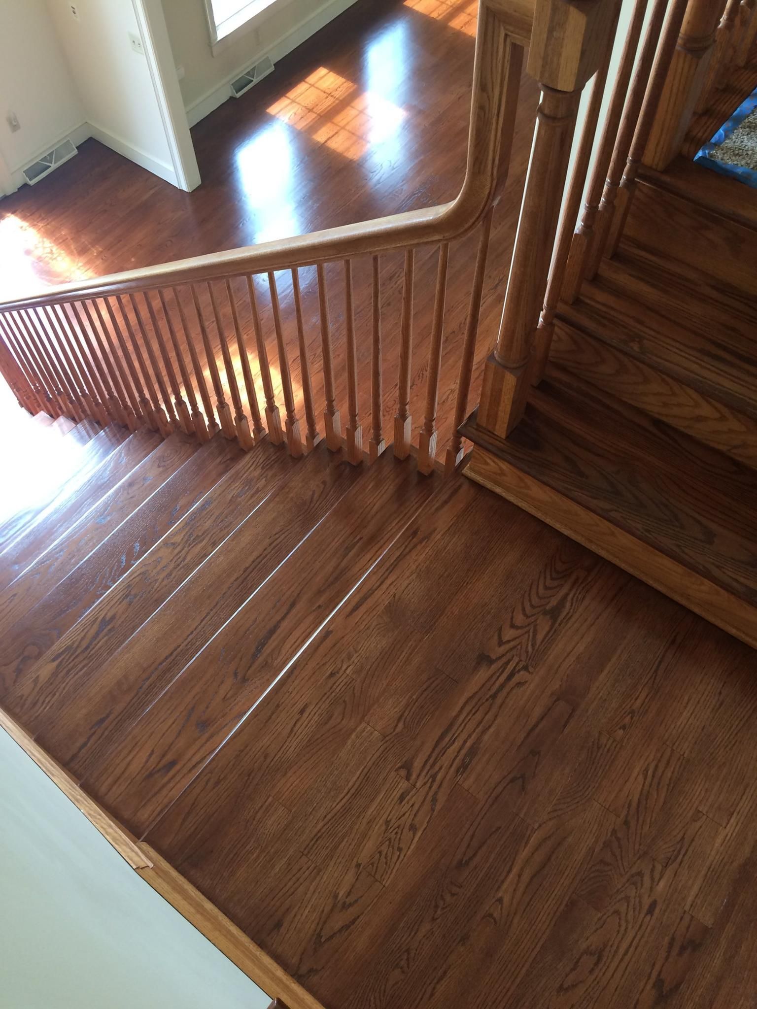 A wooden staircase with a wooden railing in a house Galebach’s Floor Finishing