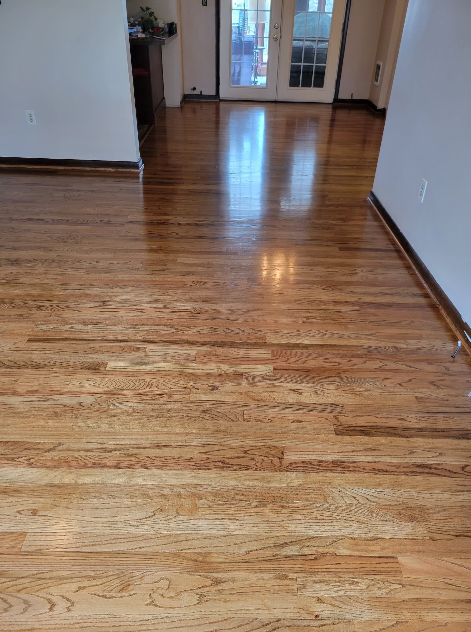 A living room with hardwood floors and a sliding glass door Galebach’s Floor Finishing