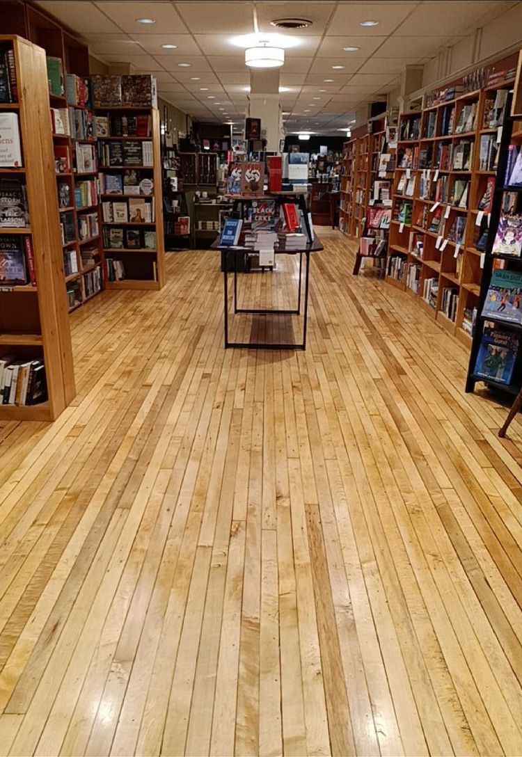 A bookstore with wooden floors and shelves filled with books.