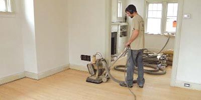 A man sanding a wooden floor. Galebach’s Floor Finishing