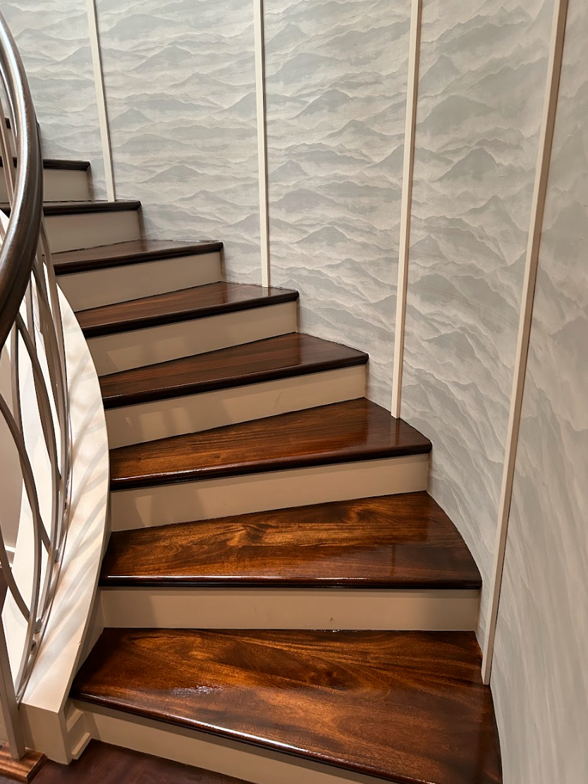 A spiral staircase with wooden steps and a metal railing by Galebach’s Floor Finishing