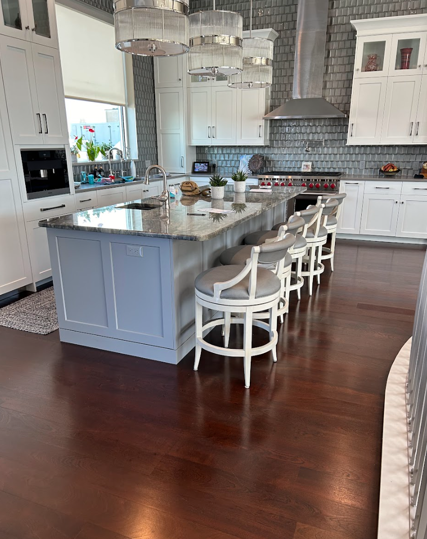 A kitchen with a large island and stools in it Galebach’s Floor Finishing.