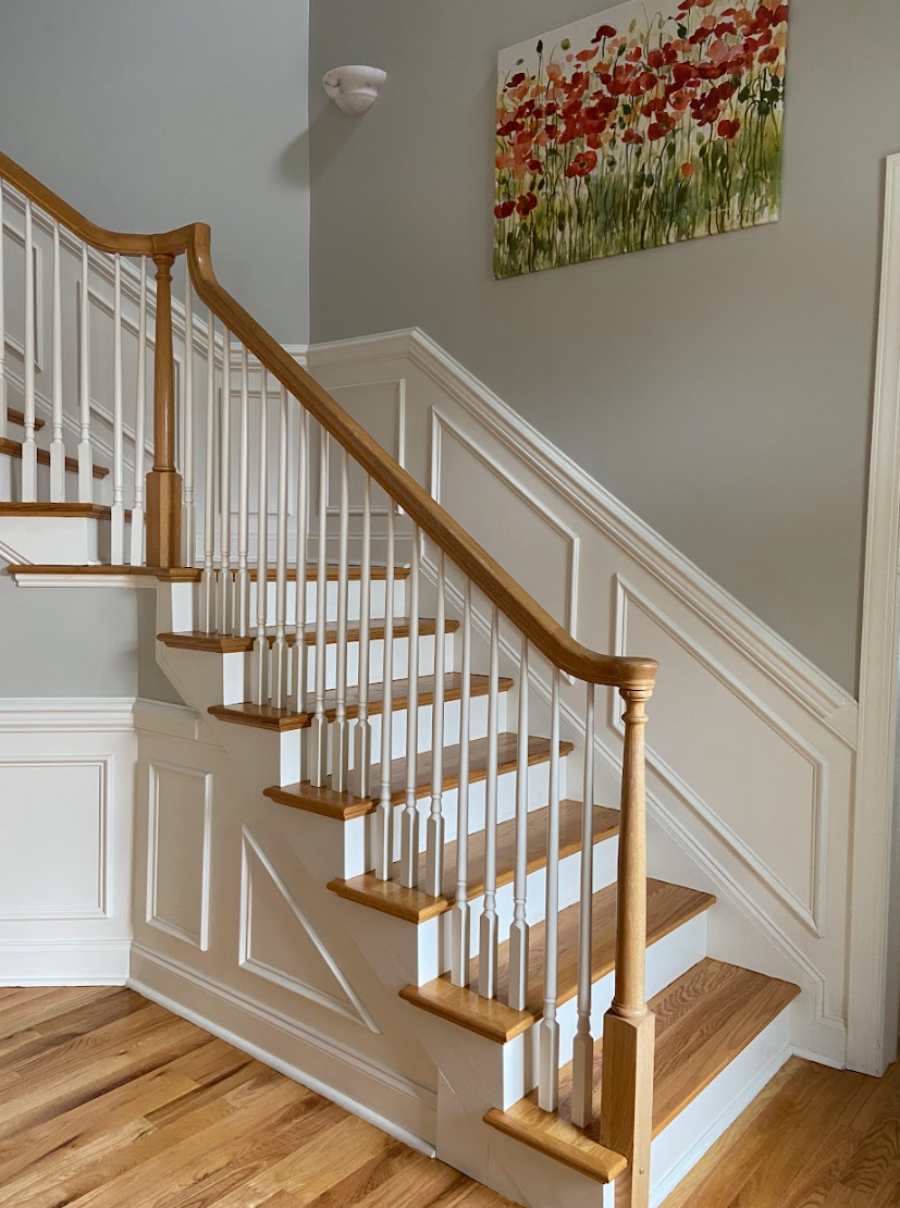 A staircase with a wooden railing and a painting on the wall above it.