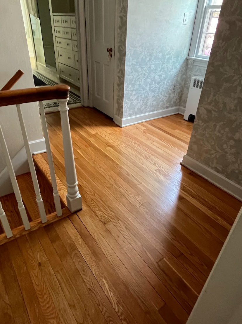 A hallway with hardwood floors and stairs in a house.
