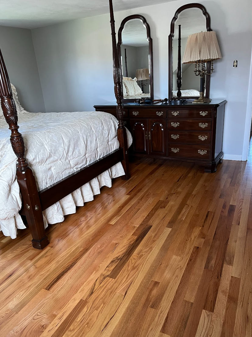 A bedroom with a four poster bed , dresser and mirrors.