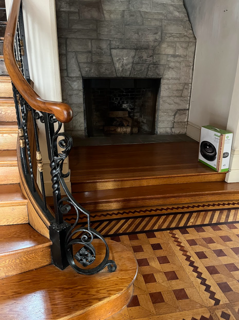 A wooden staircase with a wrought iron railing and a fireplace in the background.