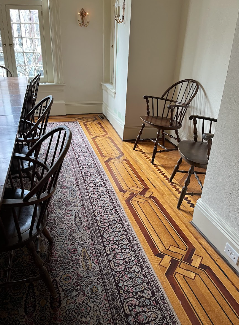 A room with a table and chairs and a rug on the floor