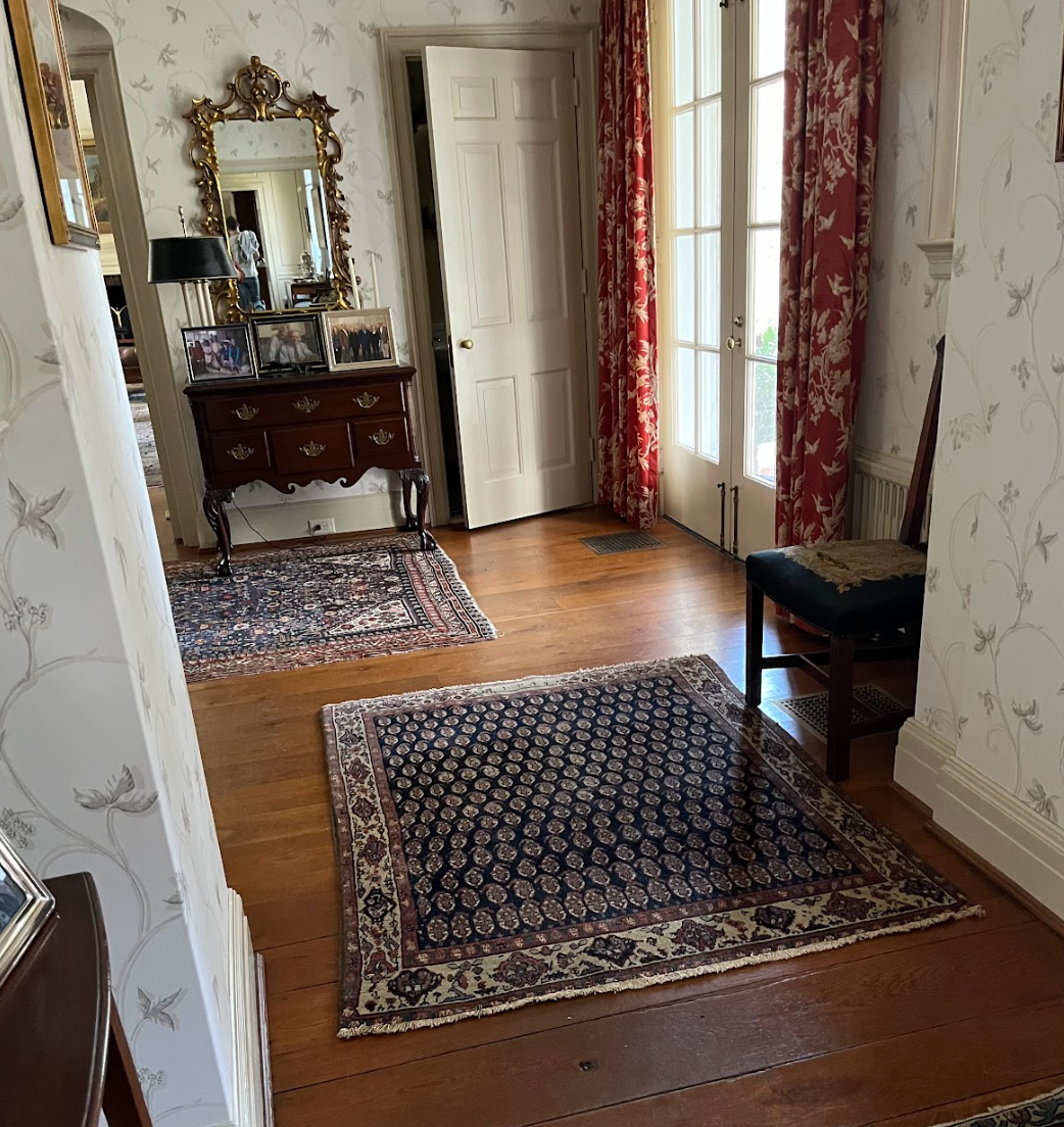 A living room with a rug on the floor and a mirror on the wall