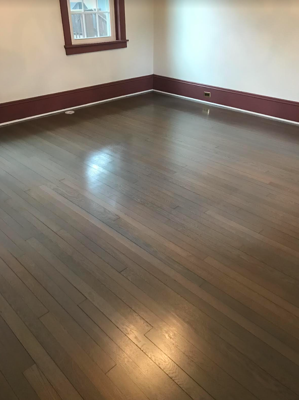 An empty room with a wooden floor and a window.
