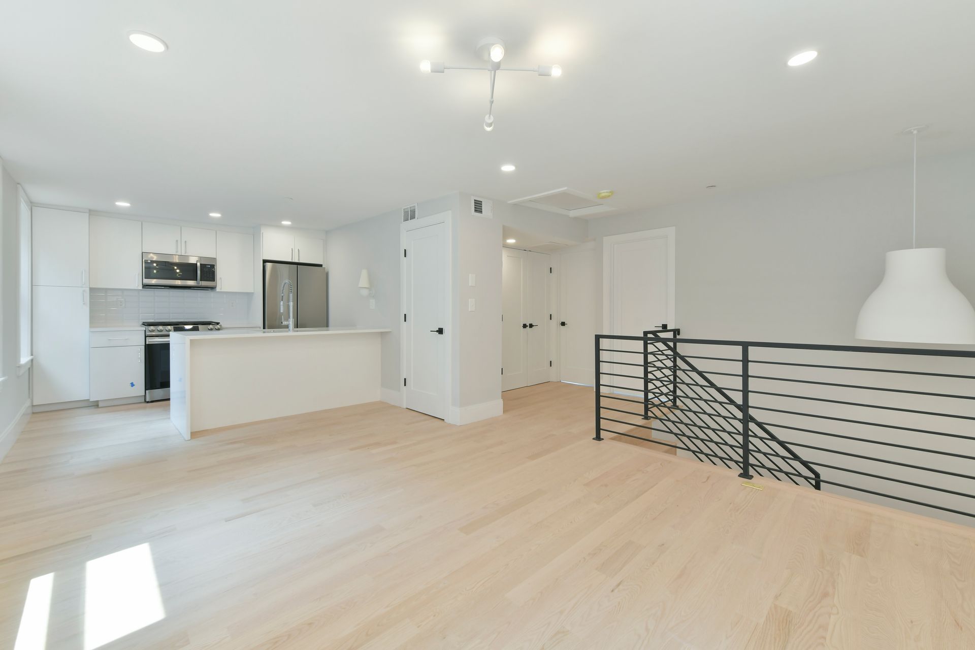 A living room with hardwood floors and a kitchen in the background