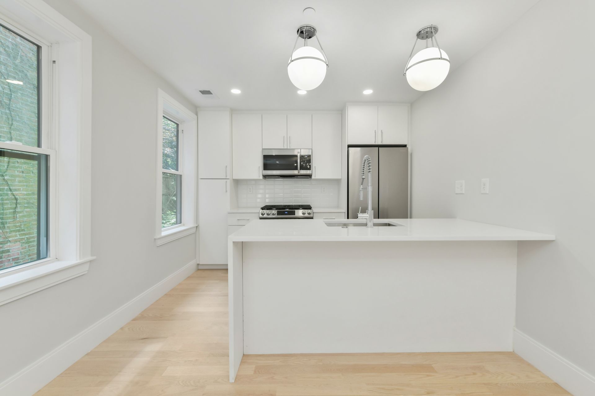 A kitchen with white cabinets and a stainless steel refrigerator.