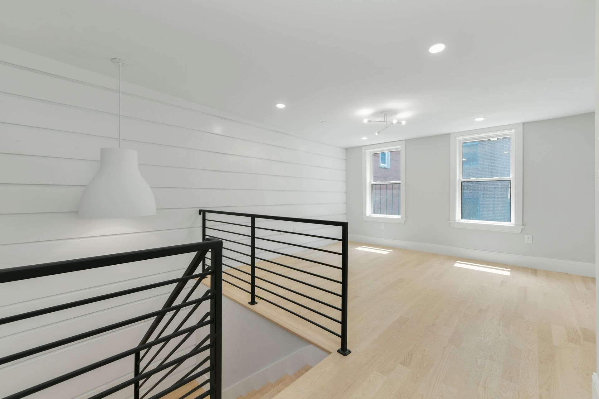 An empty room with a black railing and two windows