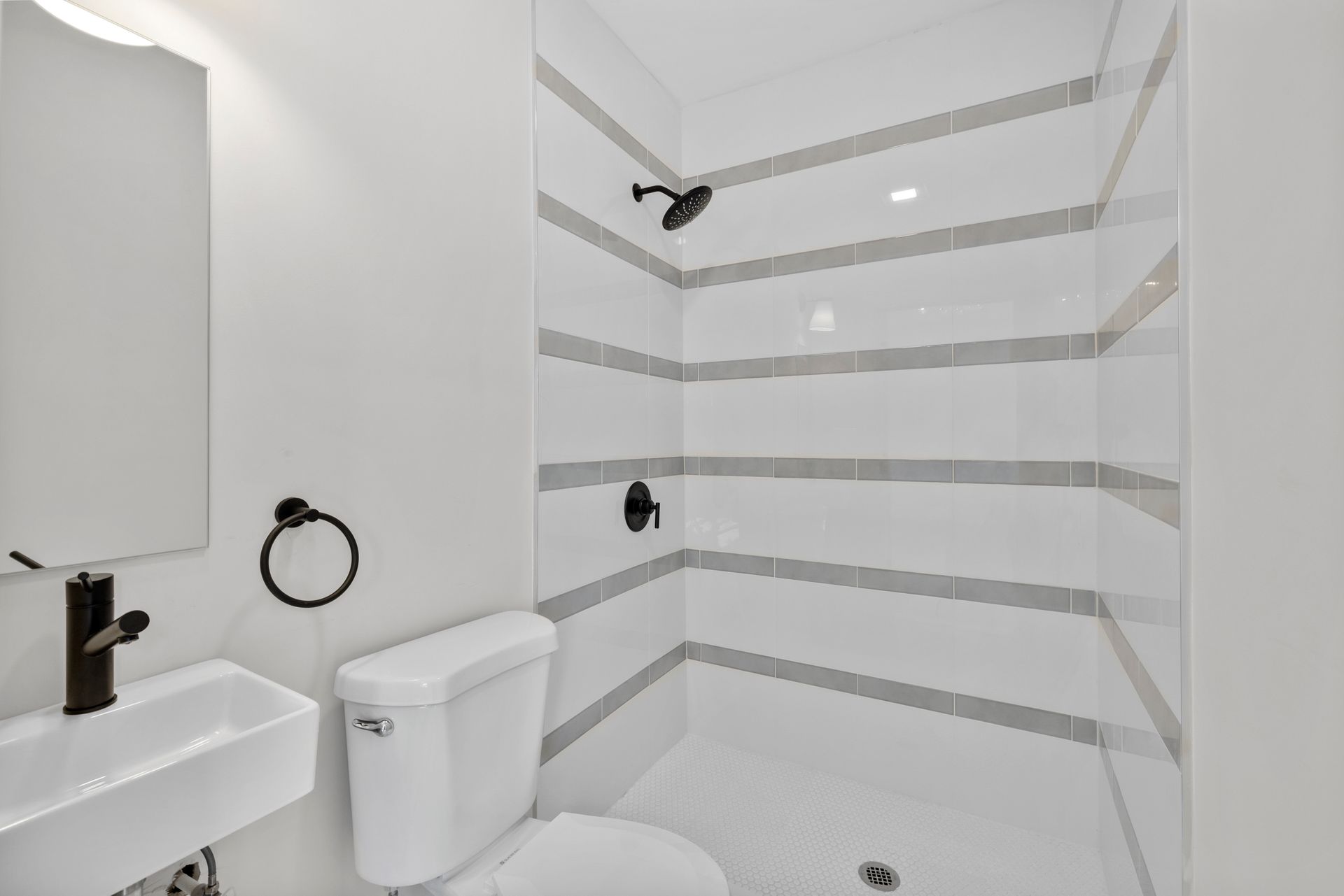 A bathroom with a toilet , sink and shower.