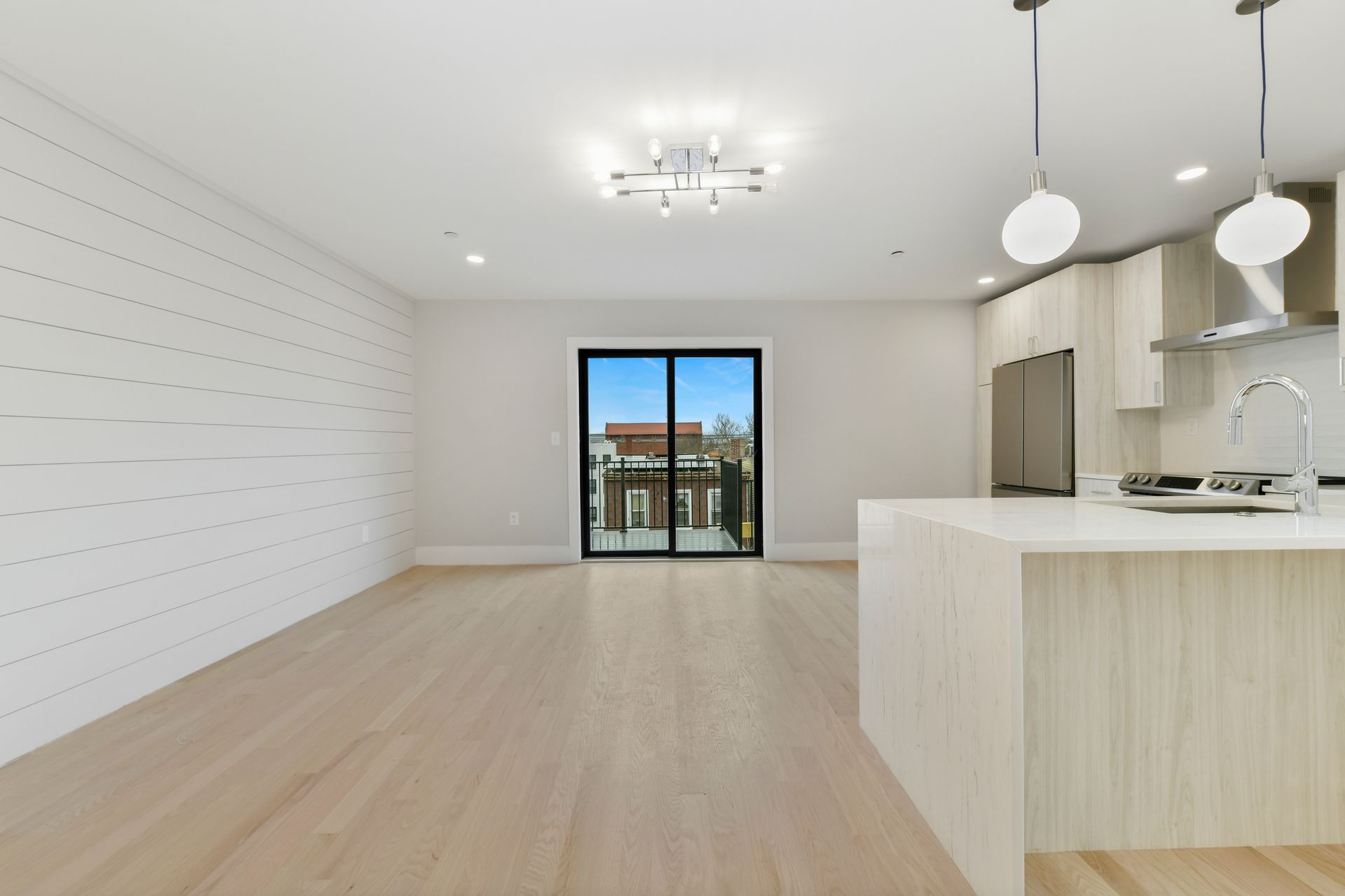 An empty room with a kitchen and sliding glass doors