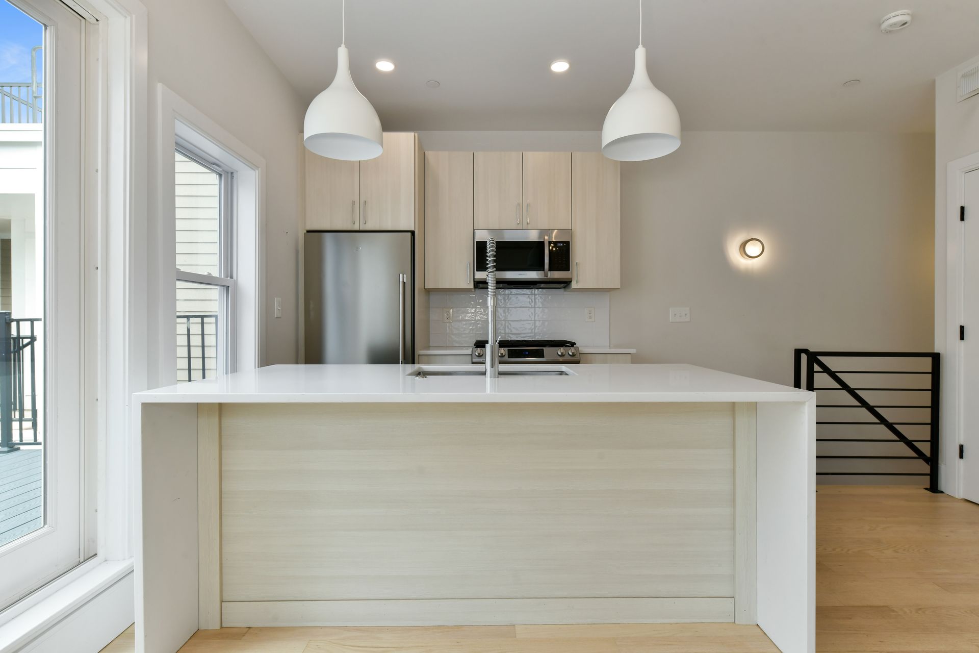 A kitchen with a stainless steel refrigerator , microwave and sink.