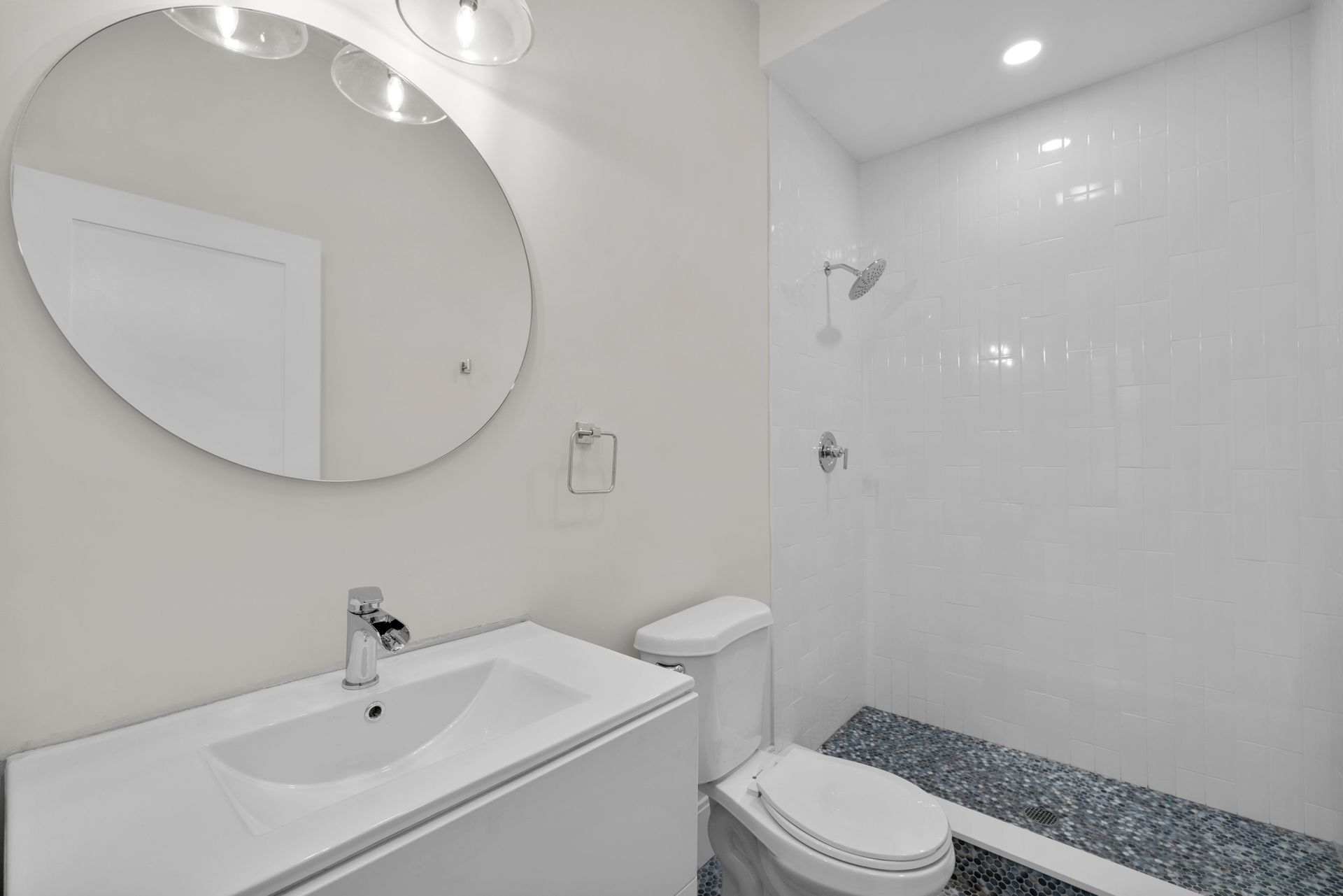 A bathroom with a toilet , sink , mirror and shower.