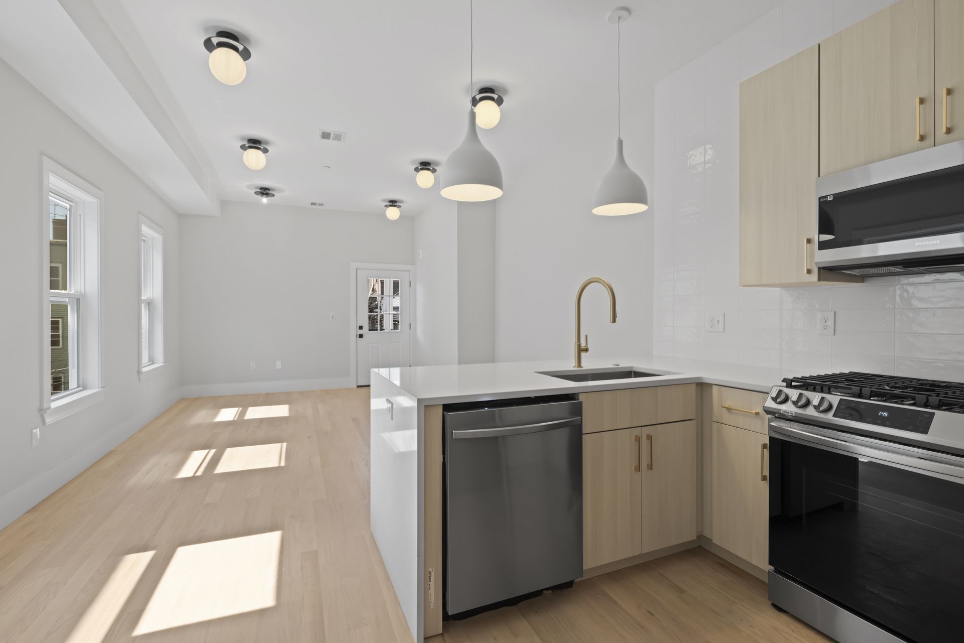 An empty kitchen with stainless steel appliances and wooden cabinets