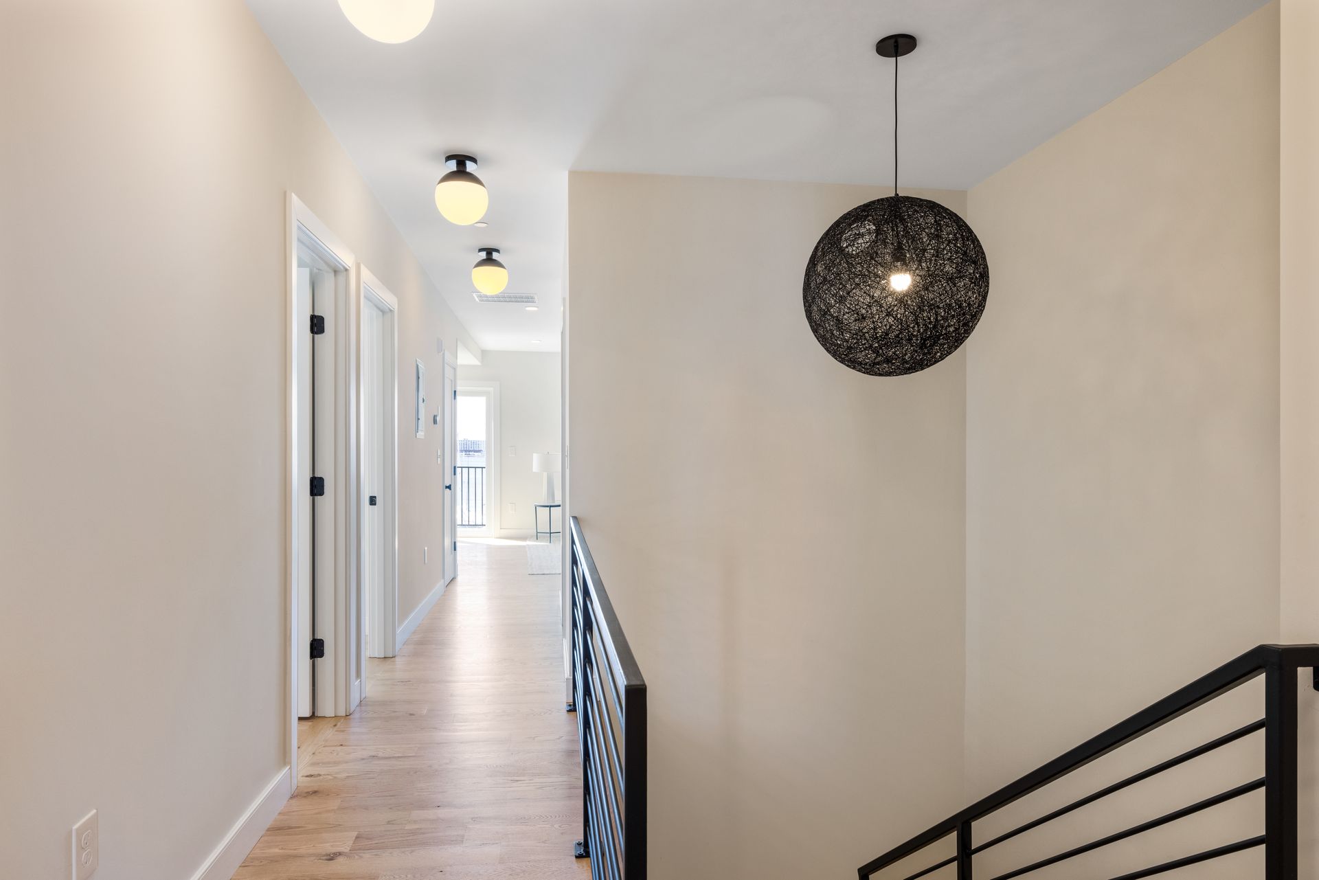 A hallway with a staircase and a light hanging from the ceiling.