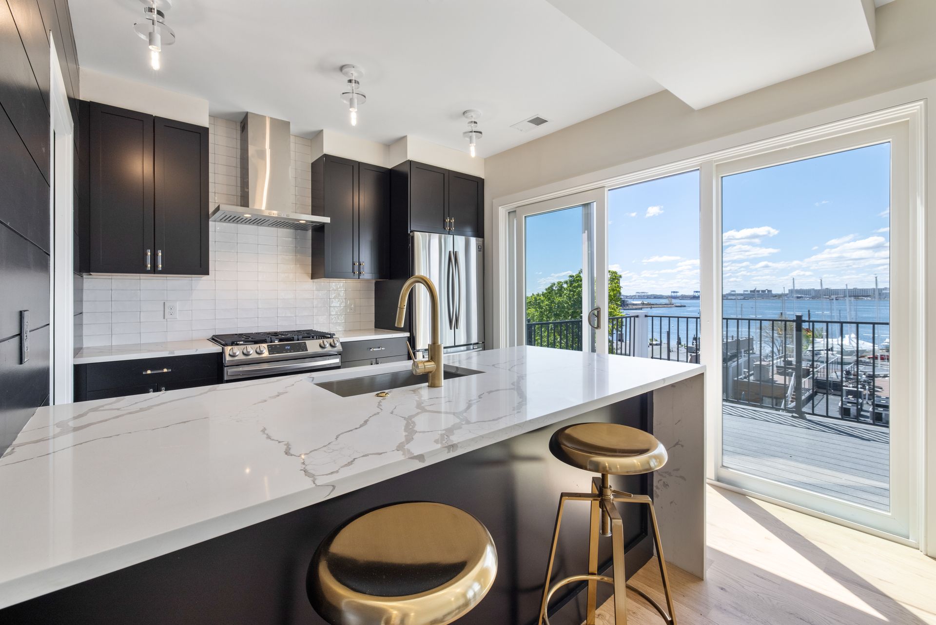 A kitchen with a large island and stools and a view of the ocean.
