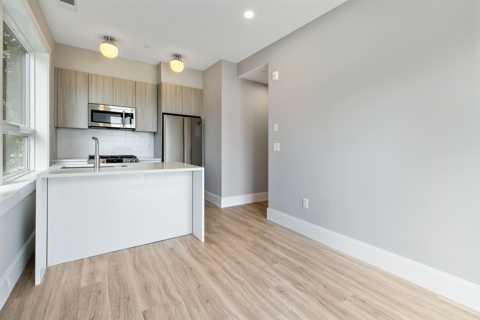 An empty apartment with a kitchen , dining room , and living room.