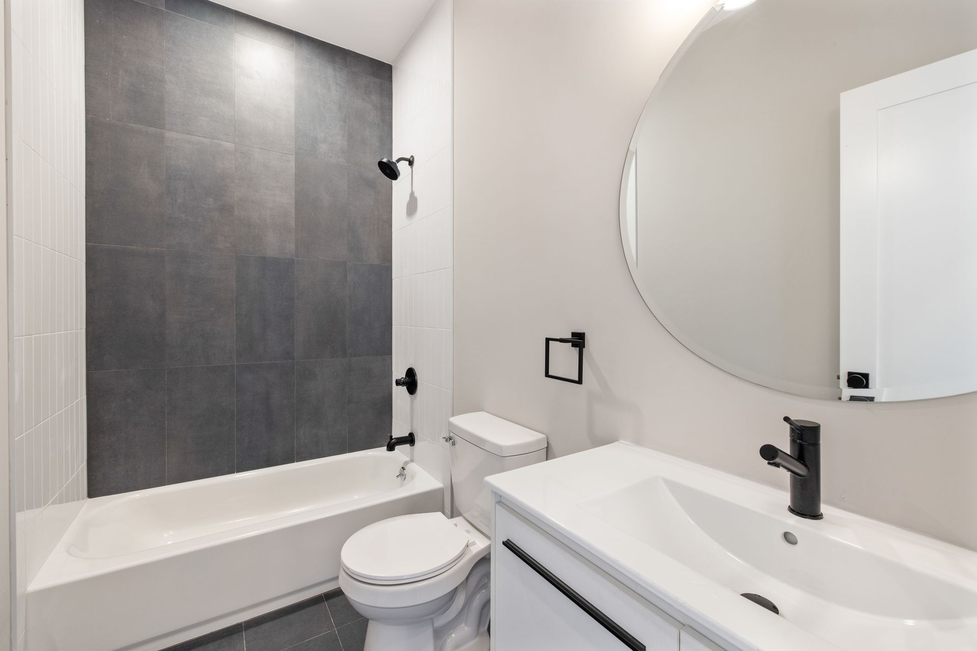 A bathroom with a toilet , sink , bathtub and mirror.
