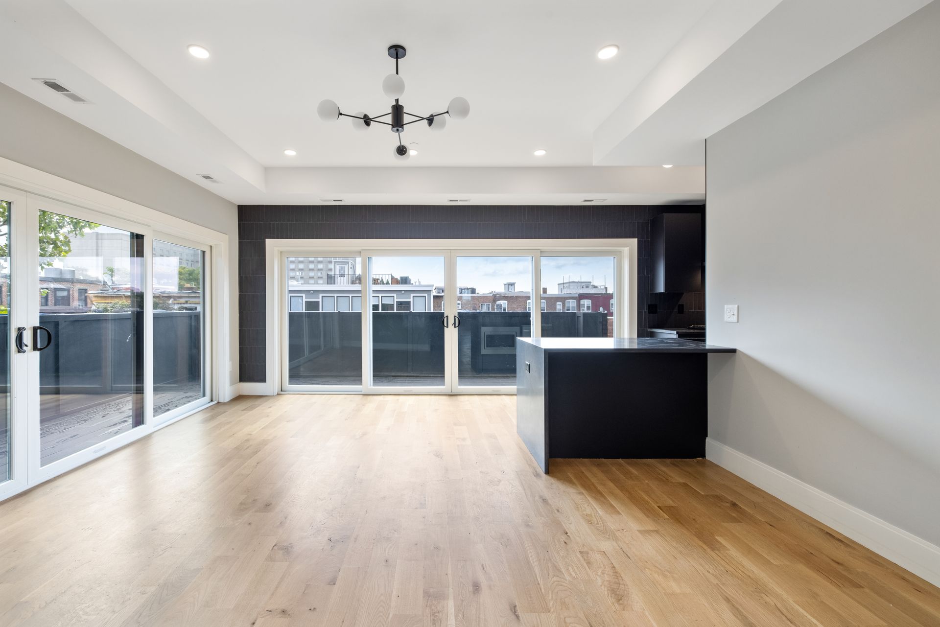 An empty living room with hardwood floors and sliding glass doors leading to a balcony.