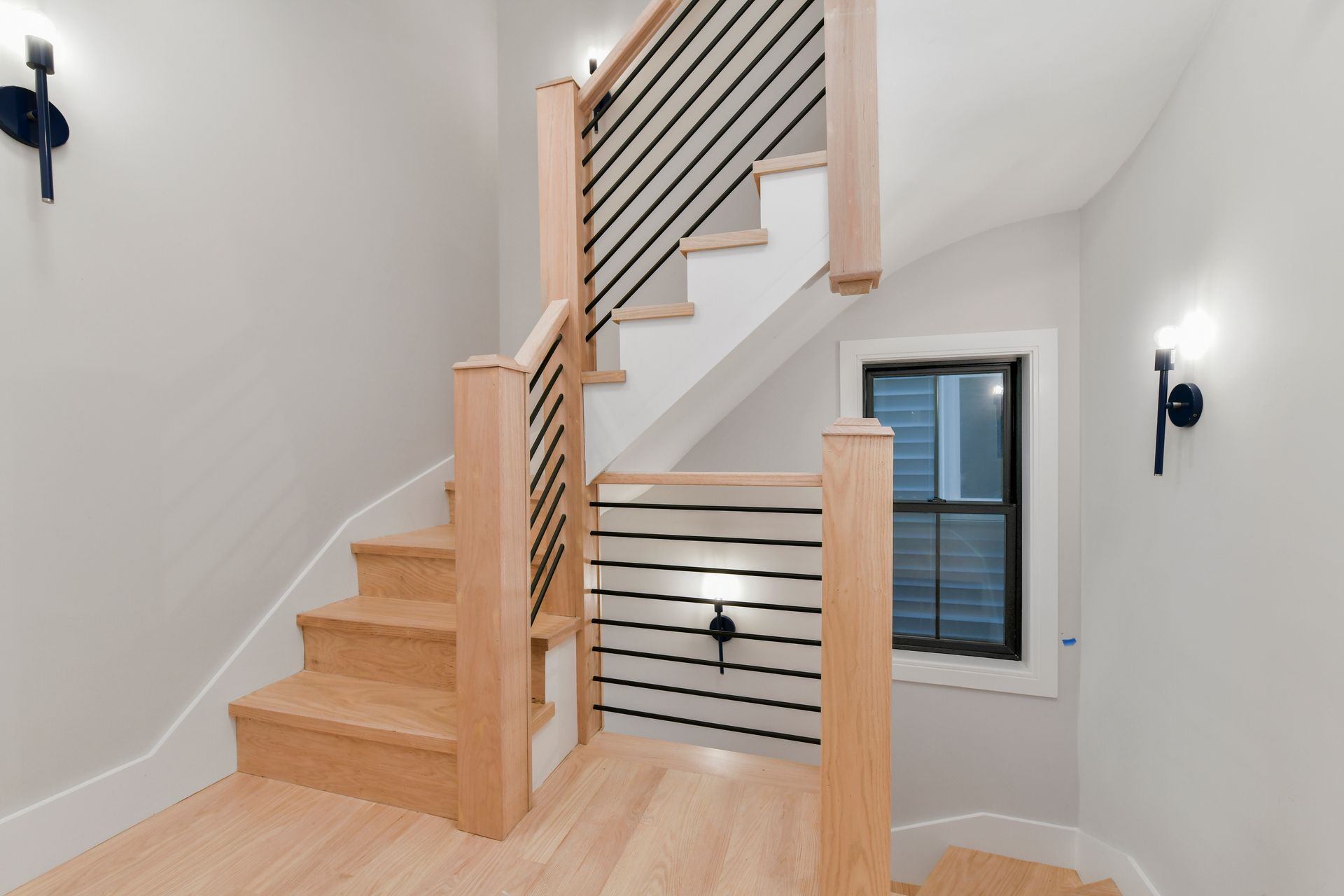 A wooden staircase with a black railing and a window