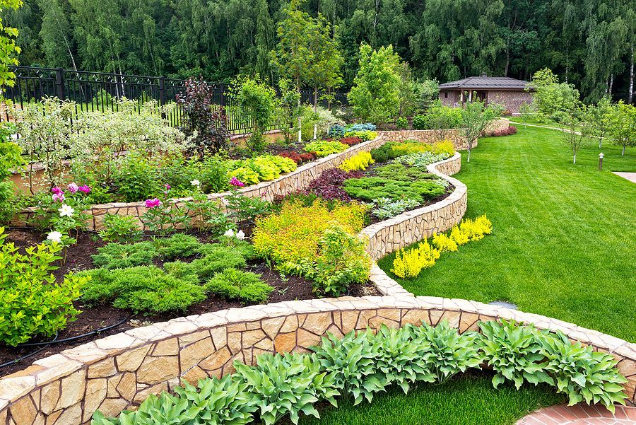 Curved stone garden beds with flowers and green lawn
