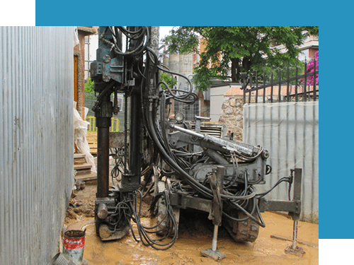 Plataforma de perforación junto a una valla y un muro, en un entorno exterior fangoso.