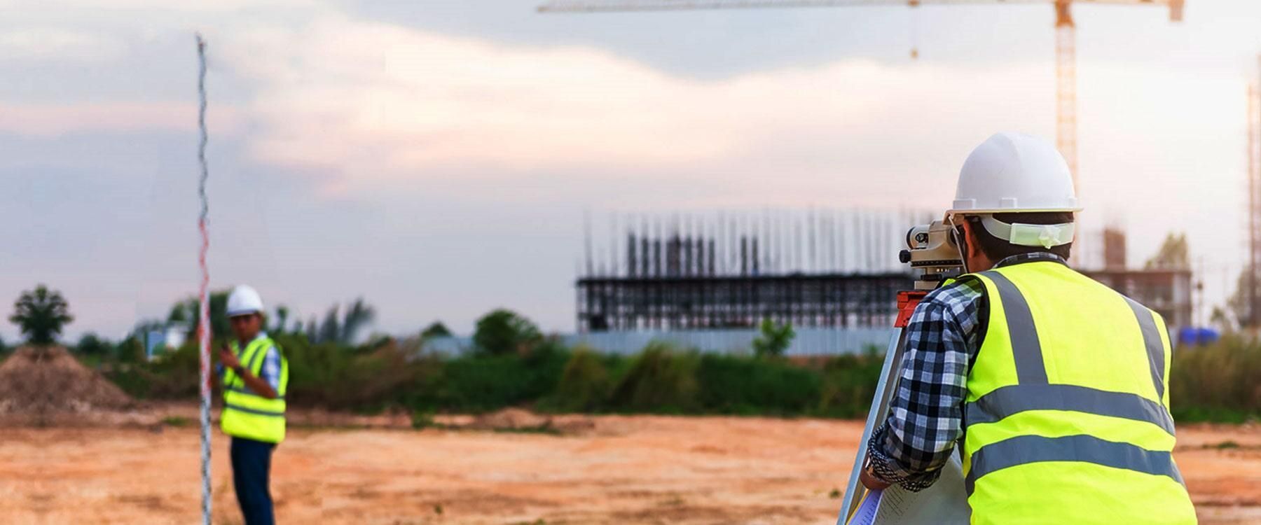 Trabajadores de la construcción que utilizan equipos de topografía en un sitio de construcción.