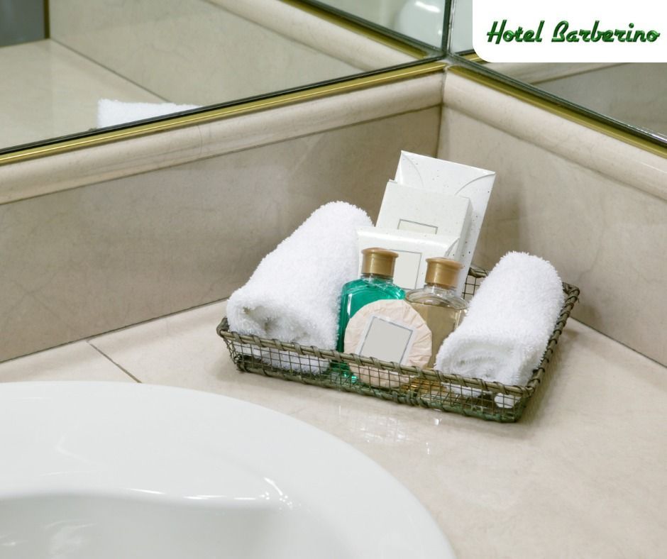 Un cesto di asciugamani e sapone è appoggiato sul bancone del bagno dell'hotel barbarino