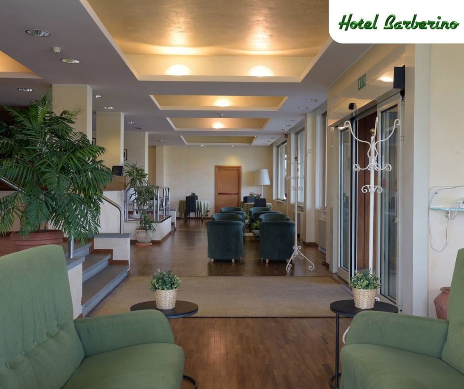 La hall di un hotel con sedie verdi e un cartello che dice hotel barberino