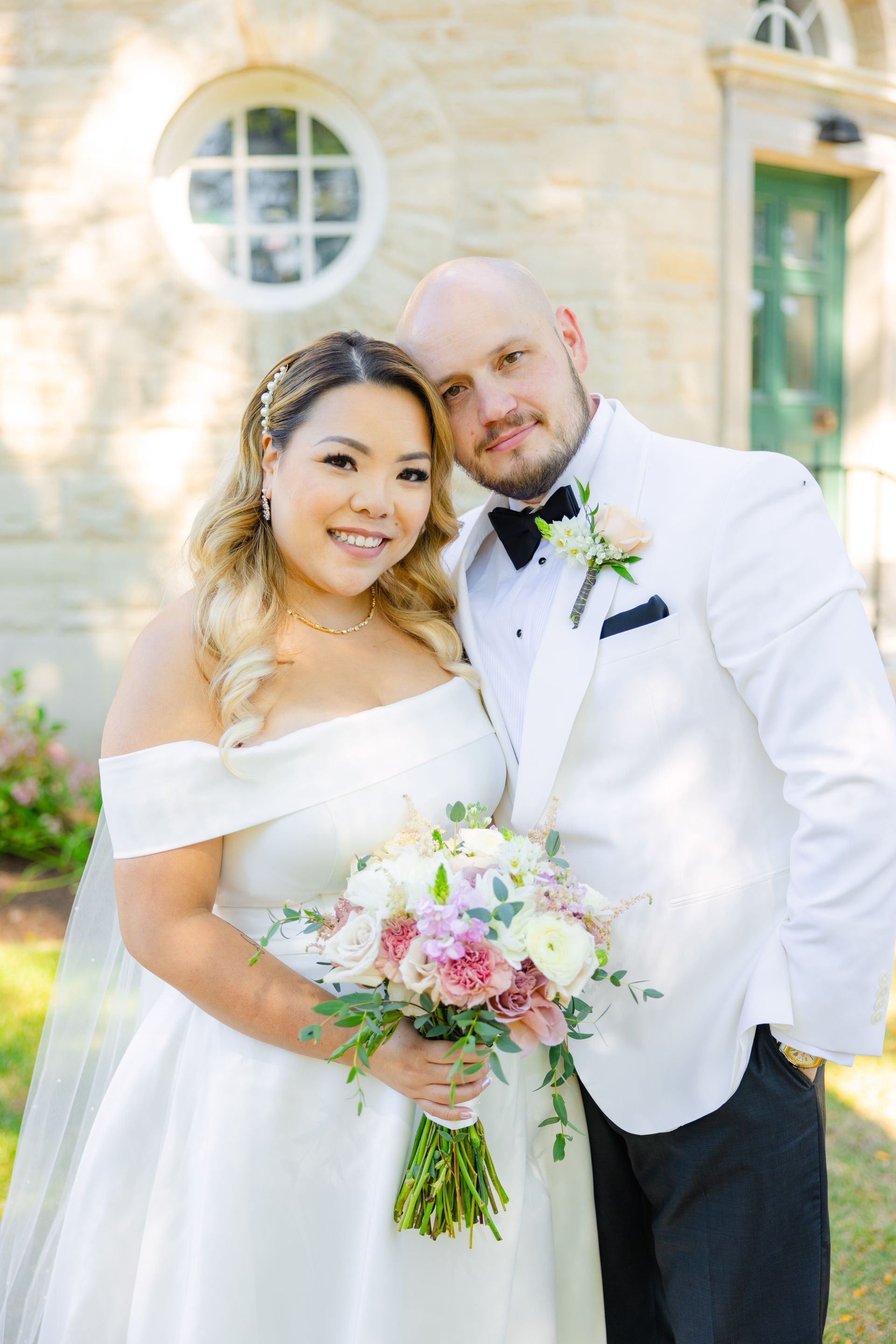 A bride and groom are posing for a picture in front of a church.