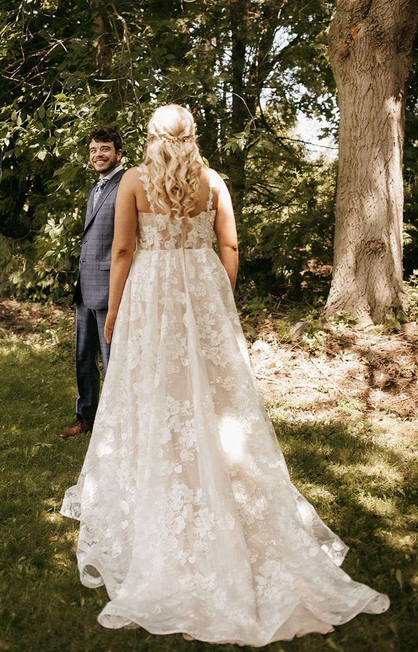 A bride in a wedding dress is standing next to a groom in a suit.